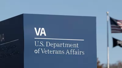 Close-up of Department of Veterans Affairs sign in Washington, D.C. with American and MIA flags on flagpole in background.