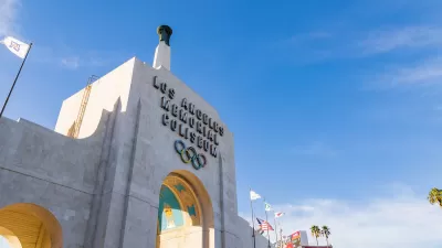 Close-up of Los Angeles Memorial Coliseum entrance arch with title and Olympic rings.