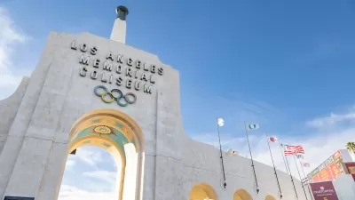 View looking up at stone entrance arch with name and Olympic rings at Los Angeles Memorial Coliseum.