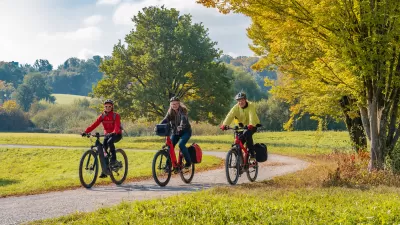 Three people riding e-bikes on park trail