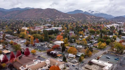 Aerial view of Grants Pass, Oregon with fall foliage and hills in background with a cloudy sky.