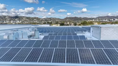 Large roof with solar panels and Los Angeles hills in background.
