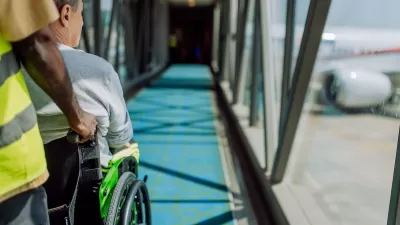 Person pusing person sitting in wheelchair down airplane ramp toward airplane at airport.