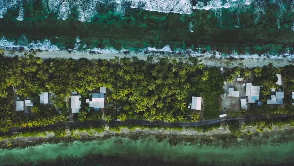 Bird's eye view of thin strip of land with palapas and palm trees in Tuvalu.