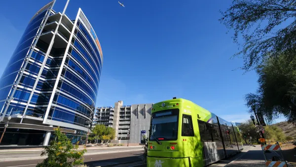 Green Tempe streetcar with downtown Tempe glass building in background.
