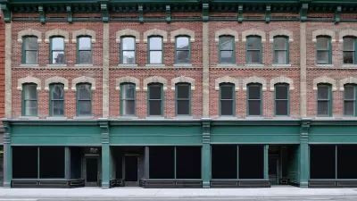 Brick building with storefronts on ground floor and apartments on two floors above.