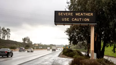 Freeway sign with "severe weather - use caution" over multilane freeway in rainy weather.
