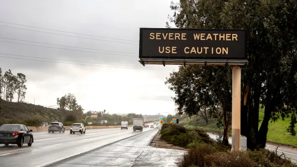 Freeway sign with "severe weather - use caution" over multilane freeway in rainy weather.