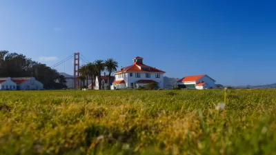 Green lawn with historic buildings and Golden Gate Bridge in background in Presidio national park site in San Francisco, California.