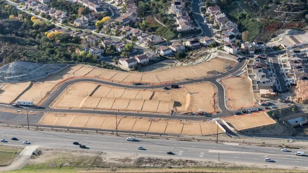Aerial view of new neifhborhood under construction with enpty lots in foreground.