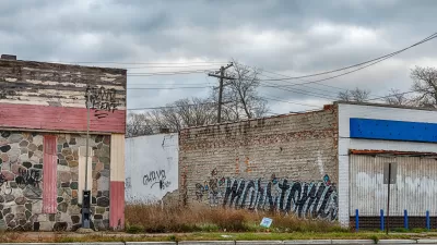 A vacant lot between two one-story brick buildings with graffiti in Detroit, Michigan