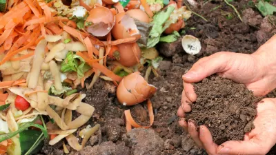 Pair of hands holding compost above pile of soil and food scraps.