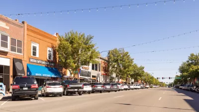 View of small-town street with brick buildings and cars parked in diagonal parking with string lights going across street in Cleveland County, Oklahoma.