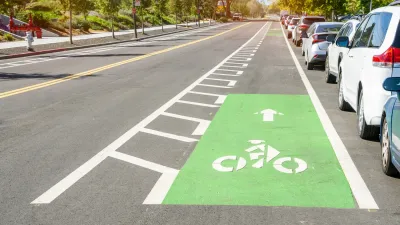 Green painted bike lane with striped buffer between car lane and curb parking lane.