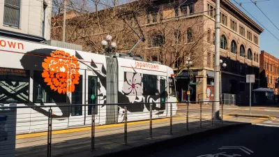 White Seattle streetcar at mid-street stop with four-story brick building in background