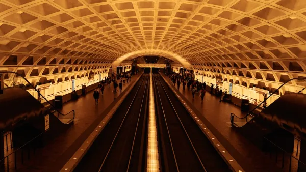View of expansive subway station with curved roof and passengers waiting for trains in Washington, D.C.