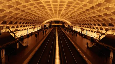 View of expansive subway station with curved roof and passengers waiting for trains in Washington, D.C.