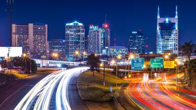 View of Nashville skyline at night with blurred highway lights in foreground.