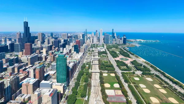 Aerial view of the Chicago Loop in summer from the south, with buildings on the left, Grant Park in the center, and Lake Michigan on the right. 