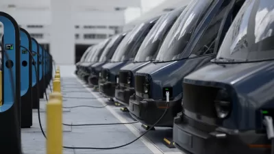 Close-up of fleet modern electric EV delivery vans being charged in covered parking garage.
