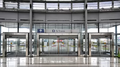 View of large glass building with glass doors and "To Trains" sign.