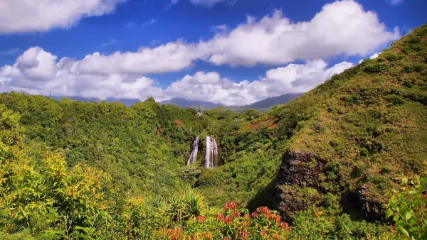 'Opaeka'a Falls on the island of Kauai surrounded by lush green forest and blue sky.