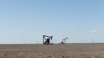 Two oil drilling derricks in vast field in West Texas.