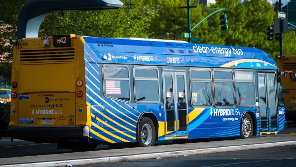 Blue hybrid NYC city bus on street.