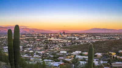 View of Tucson, Arizona at sunset with two saguaro cacti in foreground.