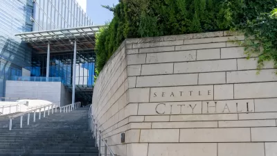 Close-up of engraved stone Seattle City Hall sign in front of wide steps leading to modern glass building.