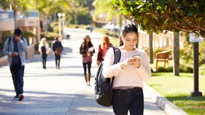 Students walking on sunny walkway on college campus.