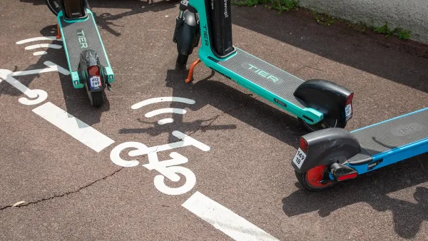 Close-up on e-scooters parked in painted designated parking area on city street.