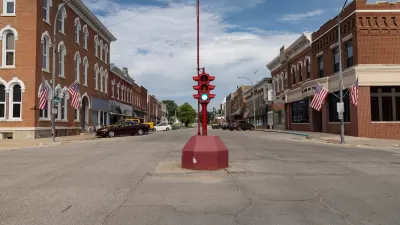 Red antique stoplight in the middle of wide intersection flanked by brick buildings in downtown rural Toledo, Iowa