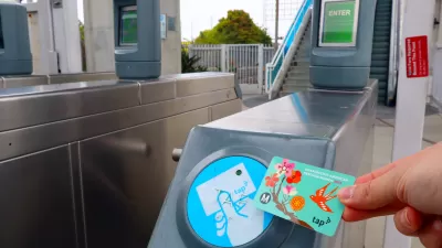 Hand holding up a TAP transit fare card to fare collection turnstile