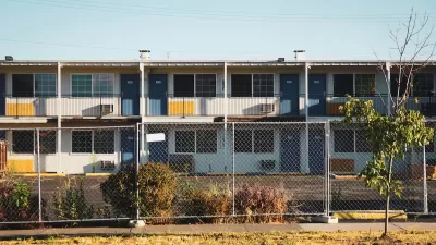 Closed, boarded-up two-story motel behind chain-link fence.