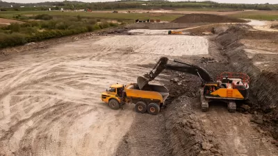 Aerial view of brownfield area with digger loading a dump truck.