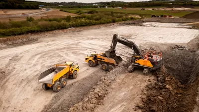 Aerial view of construction site with yellow dump truck and heavy machinery.