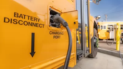 Close-up of charging port on yellow electric school bus plugged in at charging station.
