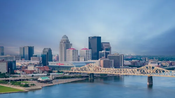 Louisville, Kentucky skyline with river and bridge in foreground at dusk.