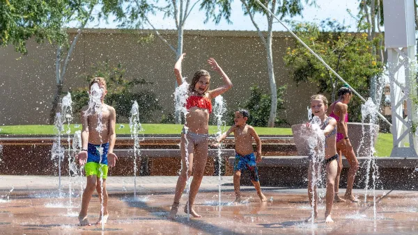 Group of children playing on splash pad in urban park.
