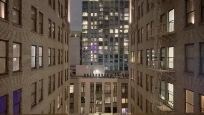 View from between tall white brick buildings in evening in downtown Los Angeles with modern office building across street.
