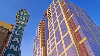 View looking up at vintage neon PORTLAND sign and modern high-rise building in Portland, Oregon.