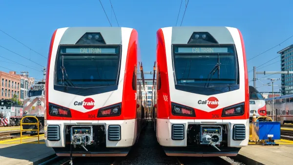 Two white and red Stadler electric Caltrain trains next to each other on a sunny day.