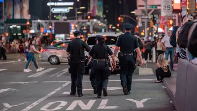 Three NYPD police officers walking away from camera in Times Square, Manhattan.