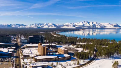 Aerial view of snowy town of Stateline, Nevada on shore of Lake tahoe with mountains in background.