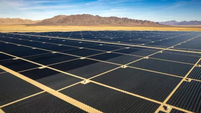 Large solar panel field in the Mojave Desert with desert mountains in background.