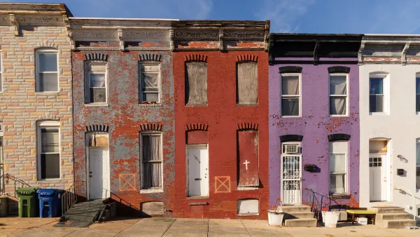 Colorful vacant, boarded-up two-story rowhouses in East Baltimore, Maryland.