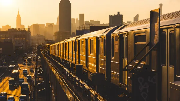 New York City subway train on elevated track in yellow light.