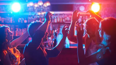 Dark shot of people dancing in front of bar with red and blue atmospheric lights