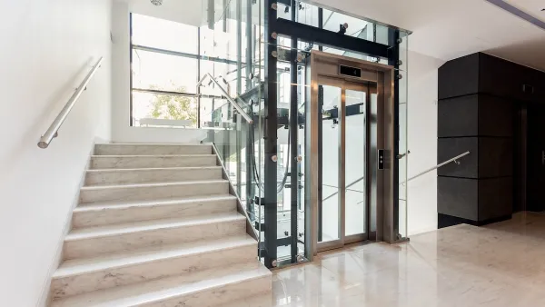 Concrete staircase next to elevator in bright building with large windows.